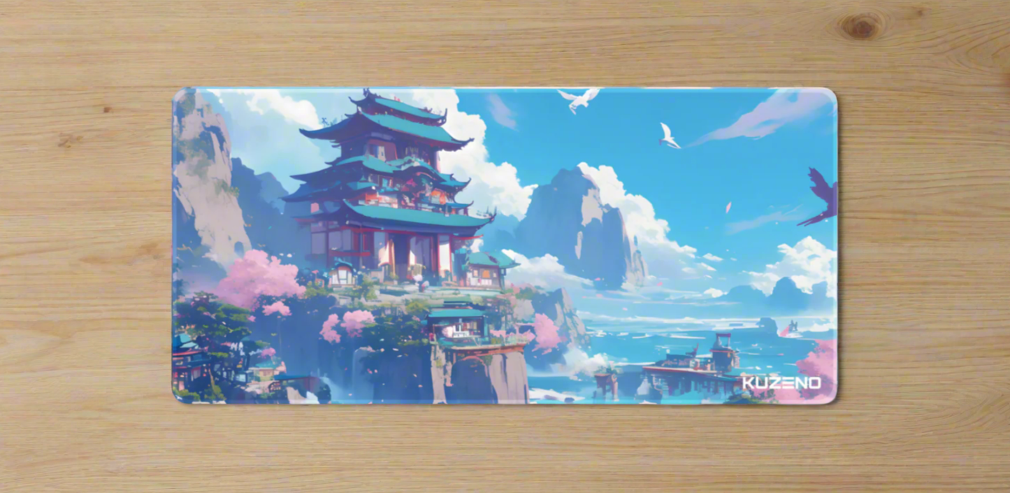 Soaring Serenity Kuzeno Gaming Mousepad displayed on a wooden desk, featuring a cliffside pagoda surrounded by cherry blossoms and overlooking a tranquil ocean.